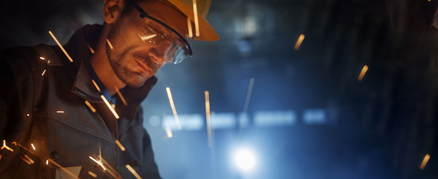 Man in work hat and sparks from welding metal